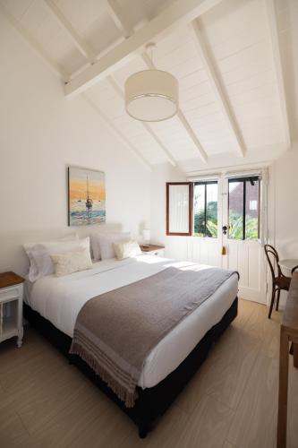 a white bedroom with a large bed and windows at Acassuso Suites in Acassuso