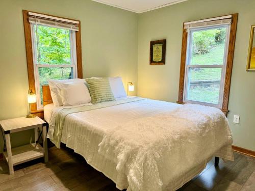 a bedroom with a white bed with two windows at Cayuga lake cottage with private lake access in Washingtonville