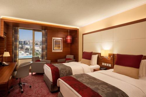 a hotel room with two beds and a desk at Crowne Plaza Amman by IHG in Amman