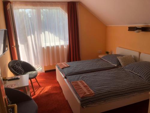 a bedroom with a bed and a window and a chair at Tekergő Vendégház in Balatonfüred