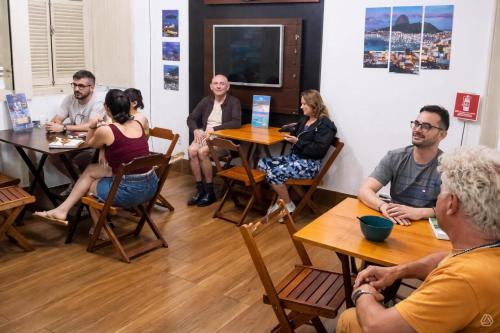 a group of people sitting at tables in a room at Rio Vibes Hostel - Hostel na Glória, AC, Social Vibe & Próximo a Lapa in Rio de Janeiro