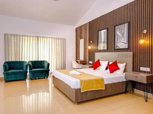 a bedroom with a bed and two green chairs at Pearl Beach Resort in Covelong