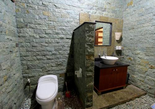 a bathroom with a white toilet and a sink at Alamanda Bingin in Uluwatu