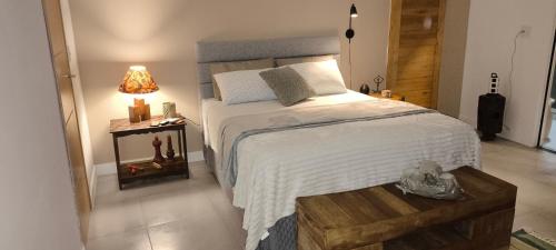 a bedroom with a large bed and a table with a lamp at Suíte Arvoredo in Saquarema