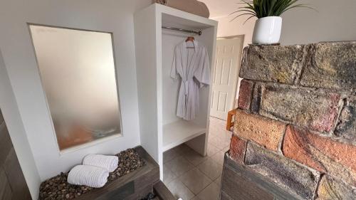 a bathroom with a white robe hanging on a wall at Santerra, Valle de Guadalupe in Valle de Guadalupe