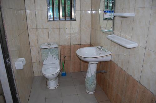 a small bathroom with a toilet and a sink at Link Hotel in Lokossa