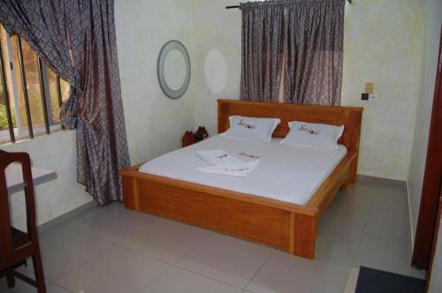 a bedroom with a wooden bed with white sheets at Link Hotel in Lokossa