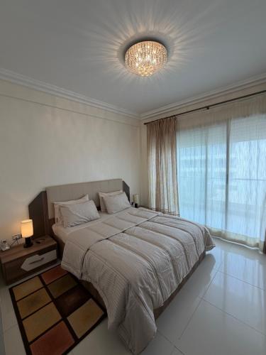a bedroom with a large bed and a chandelier at Superbe appartement pieds dans l’eau in Aourir