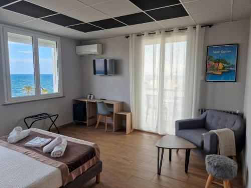a bedroom with a bed and a couch and a chair at Logis Mar I Sol - Hôtel Restaurant en bord de Mer in Saint-Cyprien