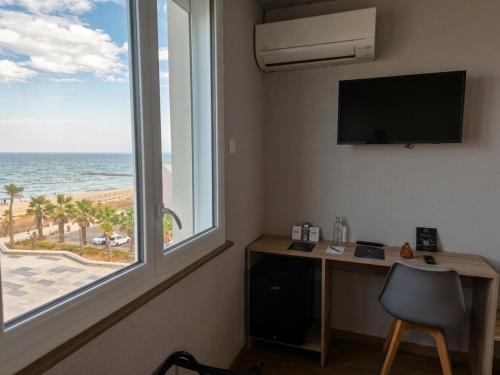 a room with a desk and a window with a view of the ocean at Logis Mar I Sol - Hôtel Restaurant en bord de Mer in Saint-Cyprien