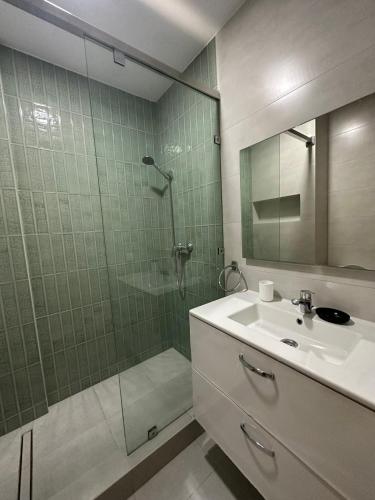 a bathroom with a shower and a sink and a mirror at Superbe appartement pieds dans l’eau in Aourir