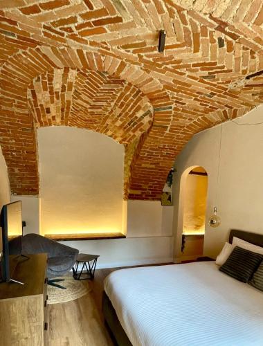 a room with a bed and a brick ceiling at La Morra Relax in La Morra
