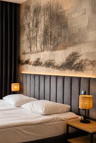 a bedroom with a bed with a painting on the wall at Zacisze Nad Nidą Resort in Pińczów