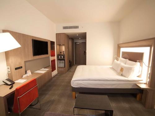 a hotel room with a large bed and a desk at Novotel Konya in Konya