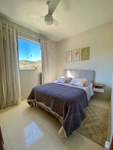 a bedroom with a bed with a blue blanket and a window at Apto Aconchego no Coração de Capitólio condomínio residencial in Capitólio