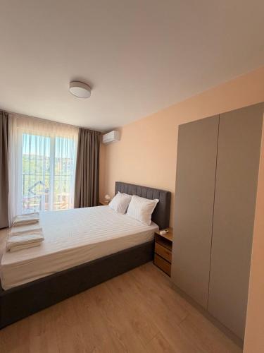 a bedroom with a large bed and a window at Студио Морски бриз in Sozopol