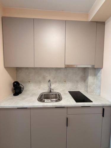 a kitchen with white cabinets and a sink at Студио Морски бриз in Sozopol