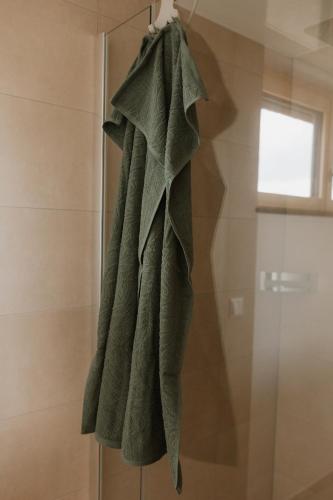 a green towel is hanging in a shower at Natururlaub by Klotz TINY HAUS a in Überlingen