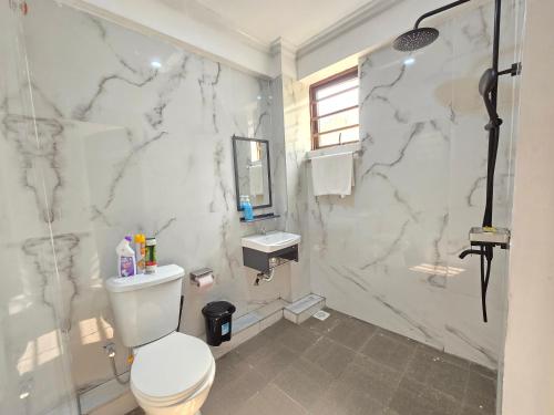 a white marble bathroom with a toilet and a shower at Marie's 2bed all-ensuite Tuffoam 310 in Kisumu