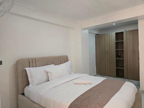a bedroom with a bed with white sheets and a window at Marie's 2bed all-ensuite Tuffoam 310 in Kisumu