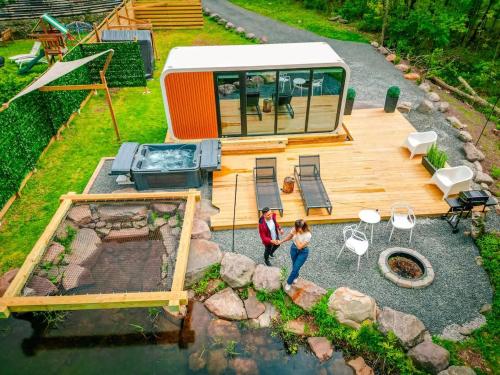 a woman standing on a wooden deck next to a rv at Romantic tiny Pod for Two HotTub Pond FirePit in Haines Falls
