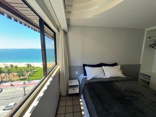 a bedroom with a bed and a view of the ocean at Flats beira mar - praia da costa in Vila Velha