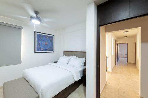 a bedroom with a white bed and a hallway at Rooftop Oasis Steps from the Malecon in La Paz