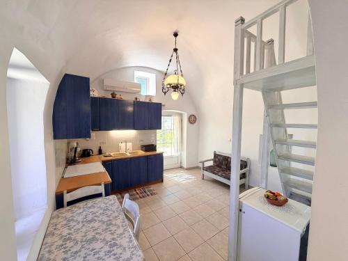 eine Küche mit blauen Schränken und eine Treppe in einem Zimmer in der Unterkunft Volta Stonehouse Apartments in Frátsia