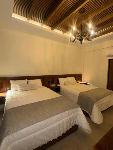a bedroom with two beds and a chandelier at HOTEL POSADA DE LA MONEDA in Zacatecas