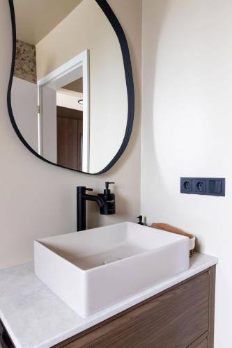 a bathroom with a white sink and a mirror at Modern Cabin with Hot Tub & Mountain views in Varmaland