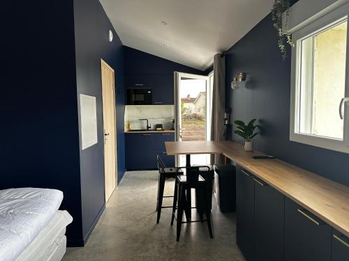 a kitchen with blue walls and a table and chairs at Studio Céleste - Clim - Parking gratuit - Proche CNPE Blayais in Braud-et-Saint-Louis