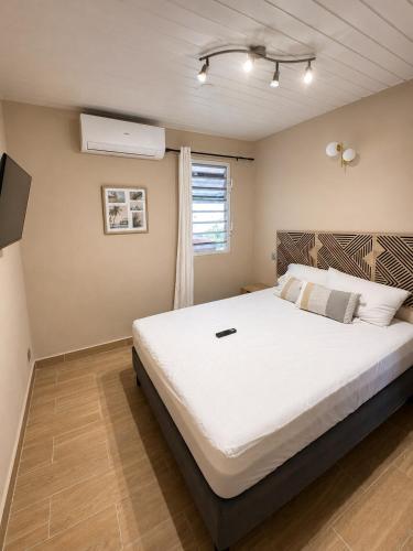 a bedroom with a large white bed and a window at Villa R-A in Kourou