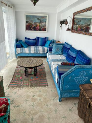 a living room with blue couches and a table at Over Sea Taghazout in Taghazout