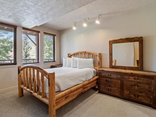 a bedroom with a wooden bed and a mirror at Crestview Condominiums by All Seasons Resort Lodging in Park City