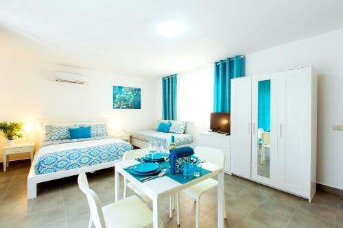 a white room with a bed and a table and a bed at FIESTA DEL CARIBE - LOS CORALES beach in Punta Cana