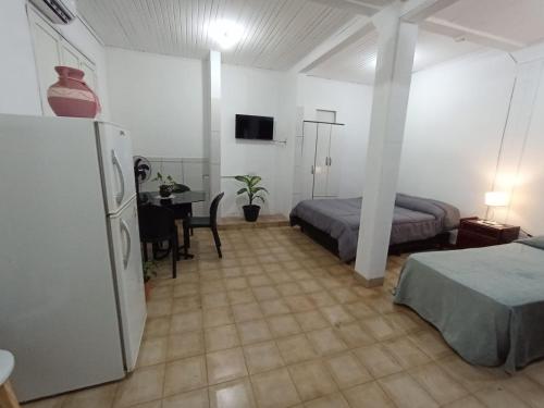 a room with a bed and a refrigerator and a table at Casa jardin 2 in Jardín América