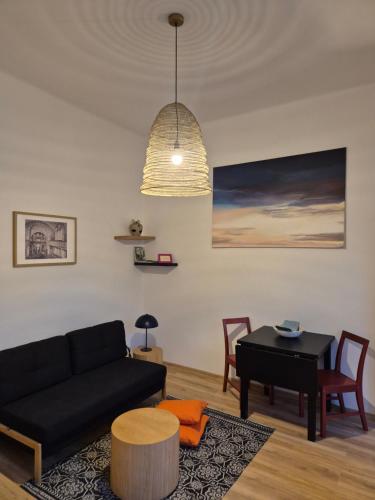 a living room with a black couch and a table at Apartmán ve dvoře in Žatec