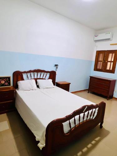 a bedroom with a large wooden bed with white sheets at Charming apartment in M'bour + 100 m² + pool in Mbour