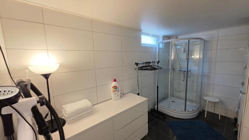 a white bathroom with a shower and a sink at Gjestehus i Tveit in Kristiansand