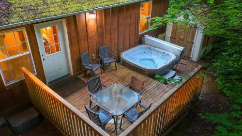 a deck with a hot tub and a table and chairs at Twin Lakes Cabin in Glacier