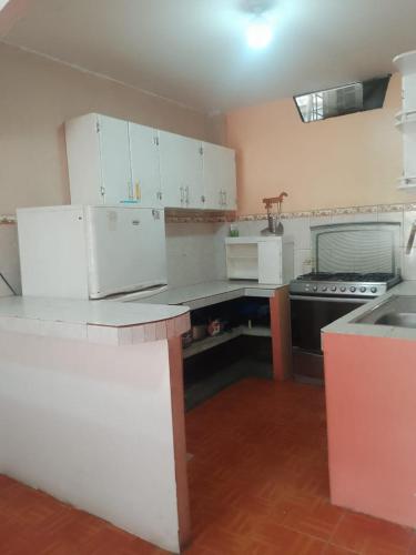 an empty kitchen with white cabinets and a sink at Alojamientos La Escapadita in Manta