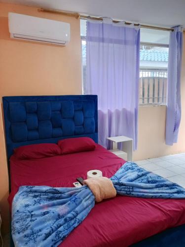 a bedroom with a red bed with a towel on it at Alojamientos La Escapadita in Manta