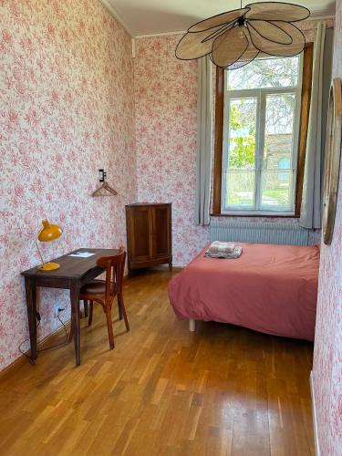 a bedroom with a bed and a table and a window at La Loge Appartement 1 in Beauquesne