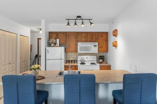 a kitchen with a counter top with blue chairs at Trailside Escape a Ski-In Ski-Out Studio in SilverStar in Vernon