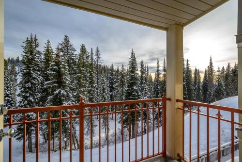 a porch with a view of snow covered trees at Trailside Escape a Ski-In Ski-Out Studio in SilverStar in Vernon