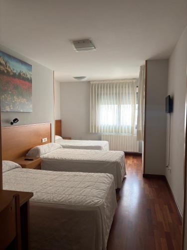 a hotel room with three beds and a window at Hostal El Poligono in Zamora