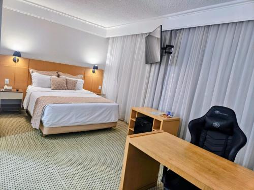 a hotel room with a bed and a desk with a computer at Guarulhos Flat Hotel in Guarulhos