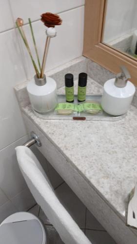 a bathroom counter with two vases and a toilet at Guarulhos Flat Hotel in Guarulhos