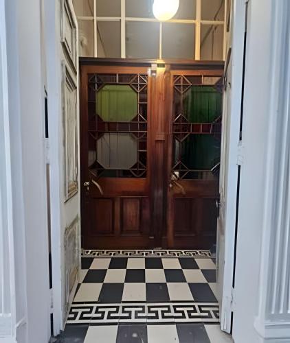 a hallway with a wooden door and a checkered floor at Casa Fran Valparaíso | Vive un Hotel Temático in Valparaíso