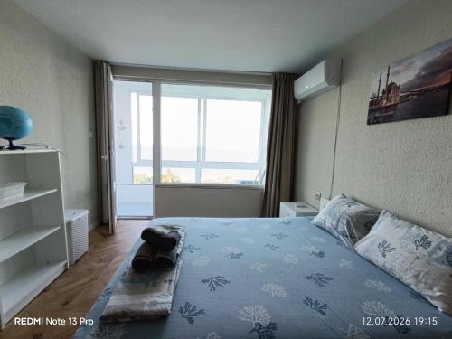 a bedroom with a bed and a large window at SEA VIEW FLORA in Burgas